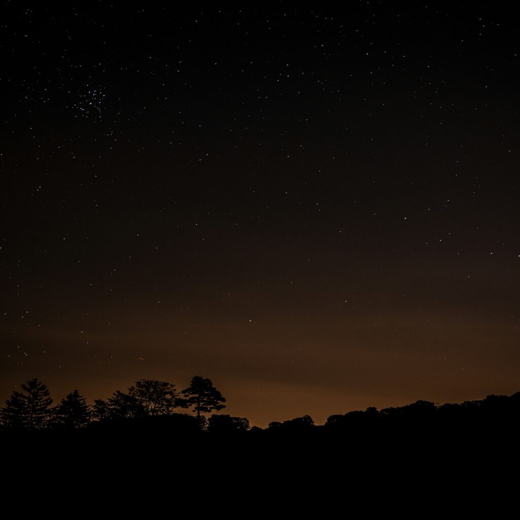 the night sky with stars above a hill